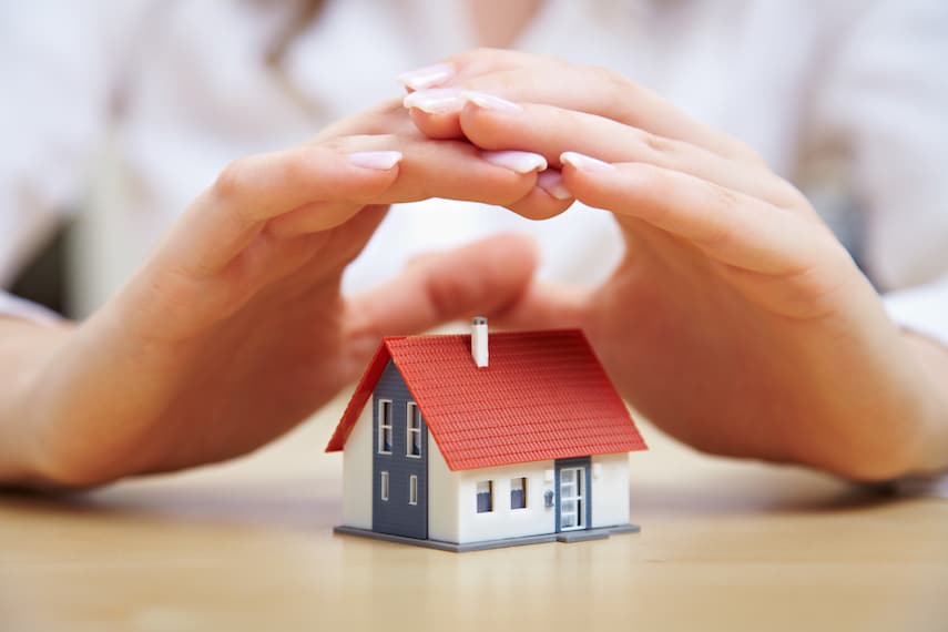 woman holding her hands over a small model house